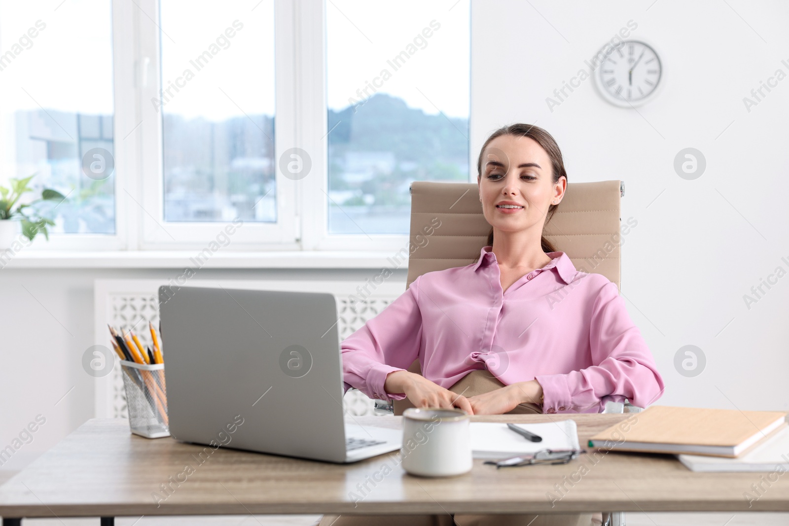 Photo of Smiling businesswoman sitting at table in office