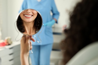 Photo of Patient looking in mirror and doctor in clinic, selective focus. Dental veneers