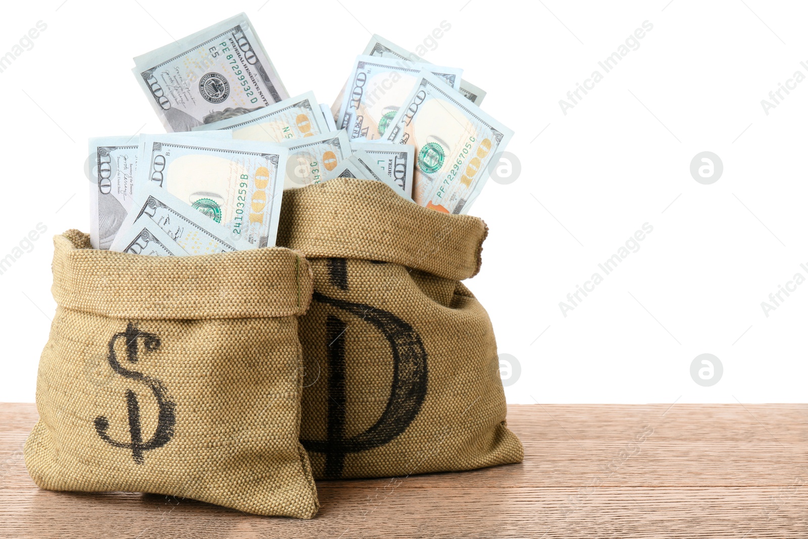 Photo of Dollar banknotes in bags on wooden table against white background, space for text