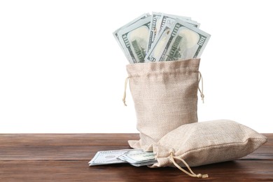 Photo of Dollar banknotes in bags on wooden table against white background, space for text