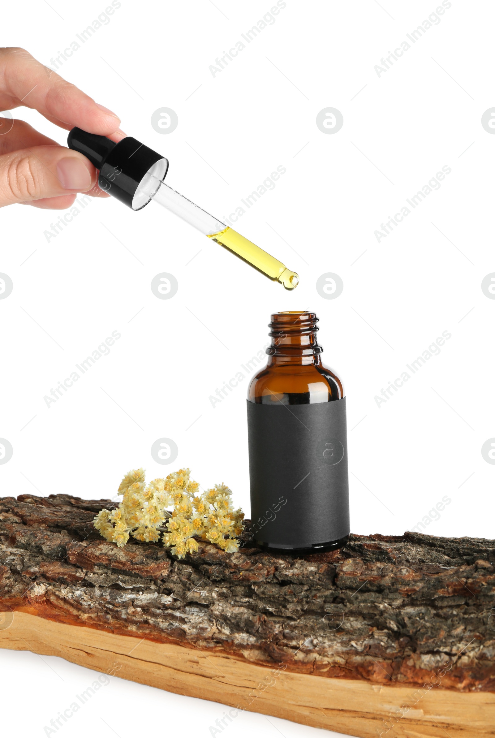 Photo of Woman dripping tincture from pipette into bottle against white background, closeup