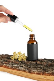 Photo of Woman dripping tincture from pipette into bottle against white background, closeup