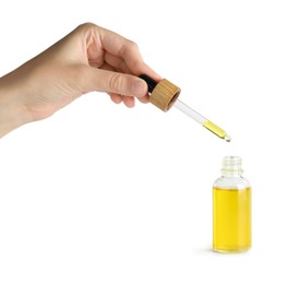 Photo of Woman dripping tincture from pipette into bottle on white background, closeup