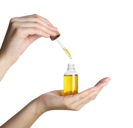 Photo of Woman dripping tincture from pipette into bottle against white background, closeup