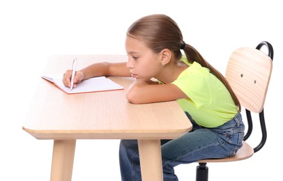 Girl with incorrect posture and notebook sitting at wooden desk on white background