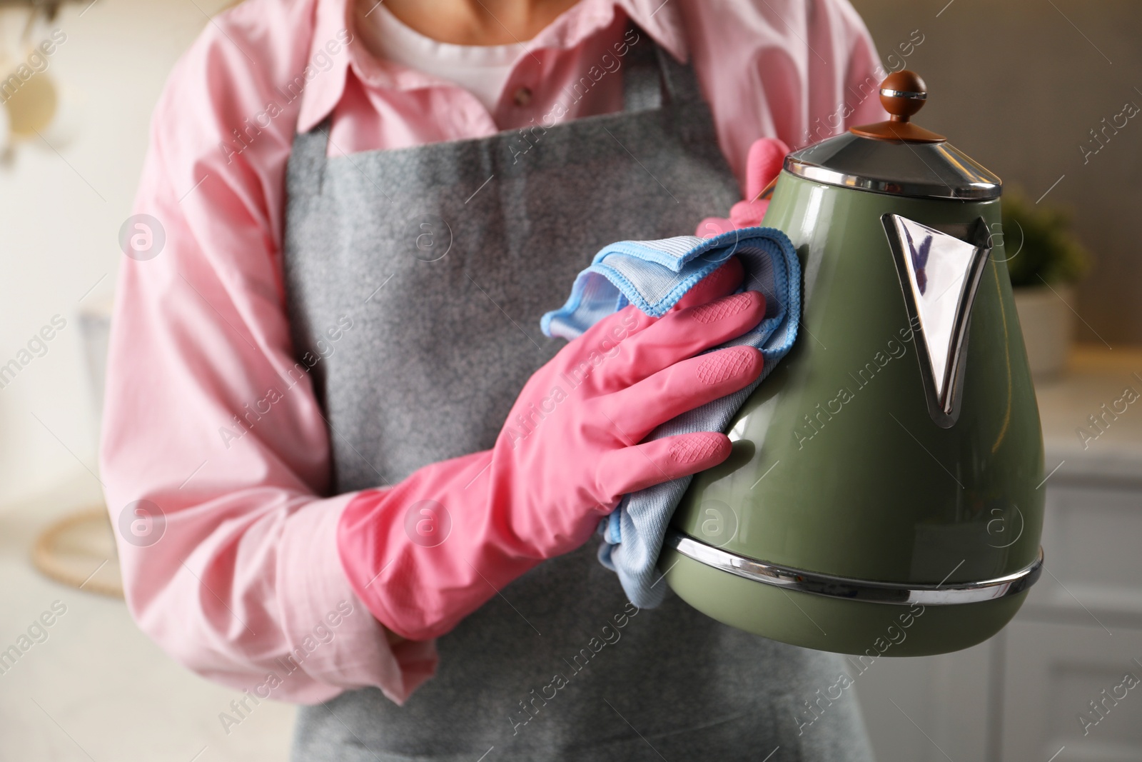 Photo of Woman wiping kettle with rag in kitchen, closeup