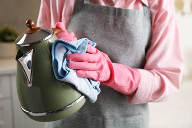 Woman wiping kettle with rag in kitchen, closeup