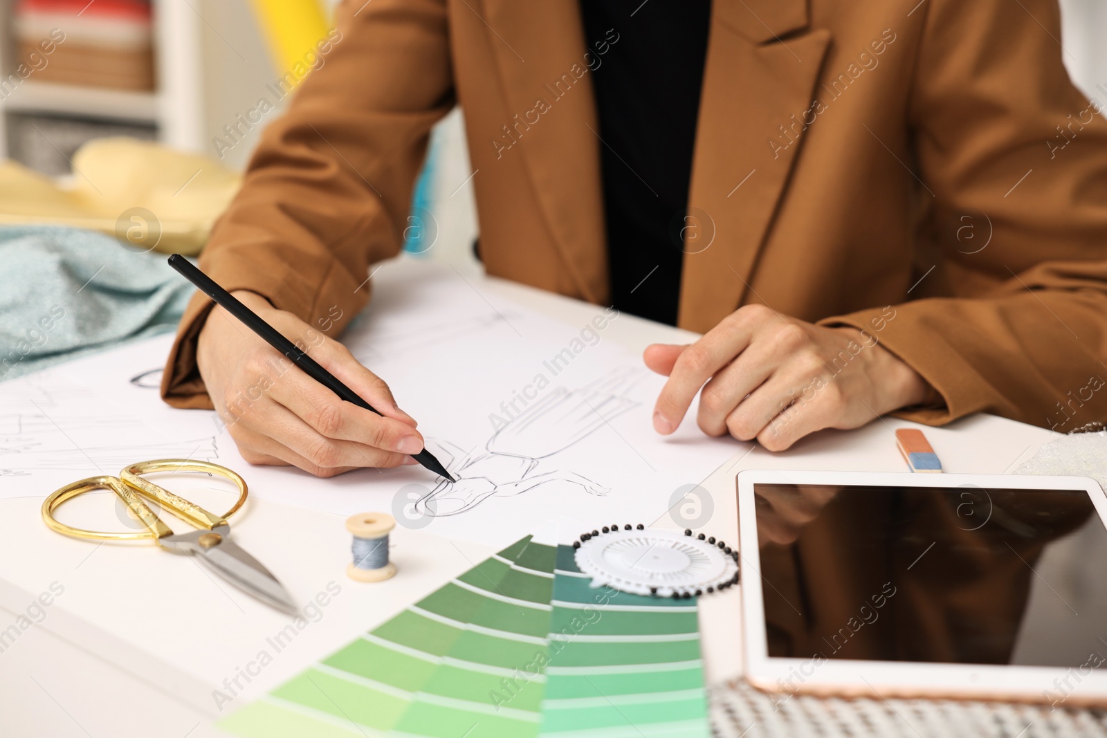 Photo of Fashion designer drawing sketch of dress at table, closeup