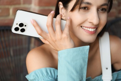 Photo of Beautiful woman with smartphone listening to voice message in outdoor cafe