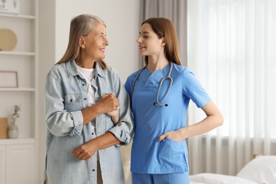 Smiling healthcare worker supporting senior patient indoors