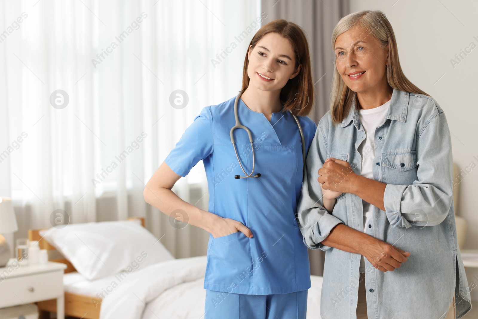 Photo of Smiling healthcare worker supporting senior patient indoors. Space for text