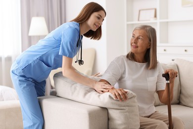 Smiling healthcare worker supporting senior patient indoors