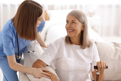 Young healthcare worker supporting senior patient indoors