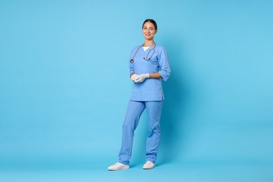 Nurse in medical uniform with stethoscope on light blue background