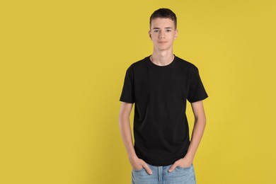 Photo of Teenage boy wearing black t-shirt on yellow background, space for text