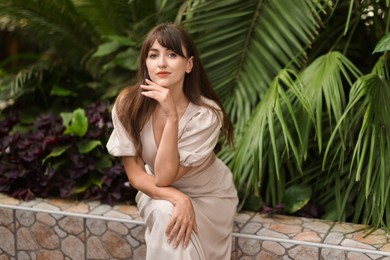 Photo of Beautiful woman posing near palm plants outdoors