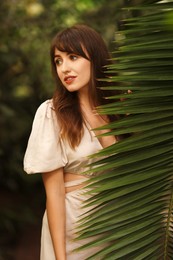 Portrait of beautiful woman with palm tree leaf outdoors