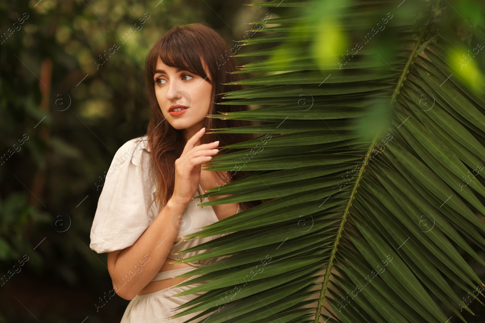 Photo of Portrait of beautiful woman with palm tree leaf outdoors