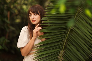 Photo of Portrait of beautiful woman with palm tree leaf outdoors