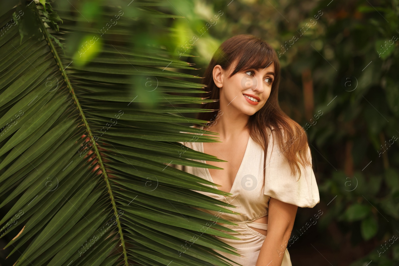 Photo of Portrait of smiling woman with palm tree leaf outdoors