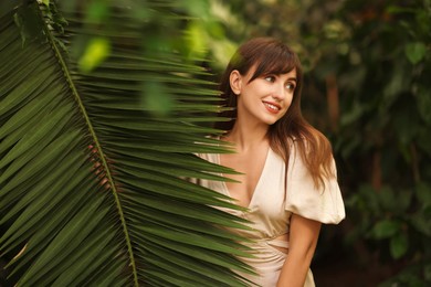 Portrait of smiling woman with palm tree leaf outdoors