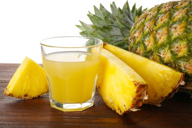 Photo of Glass with pineapple juice and fresh pineapples on wooden table against white background