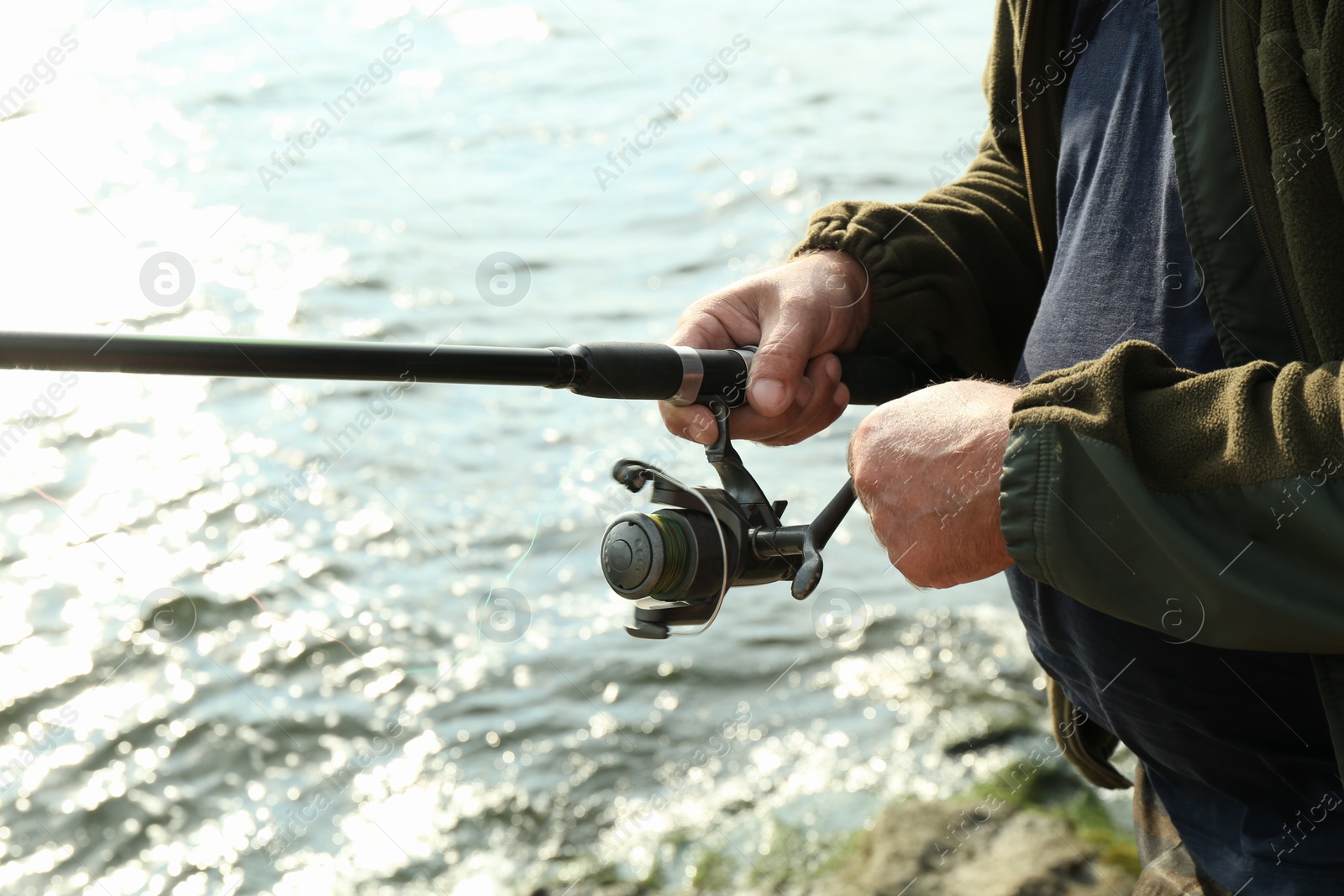 Photo of Fisherman with rod fishing near lake at summer, closeup