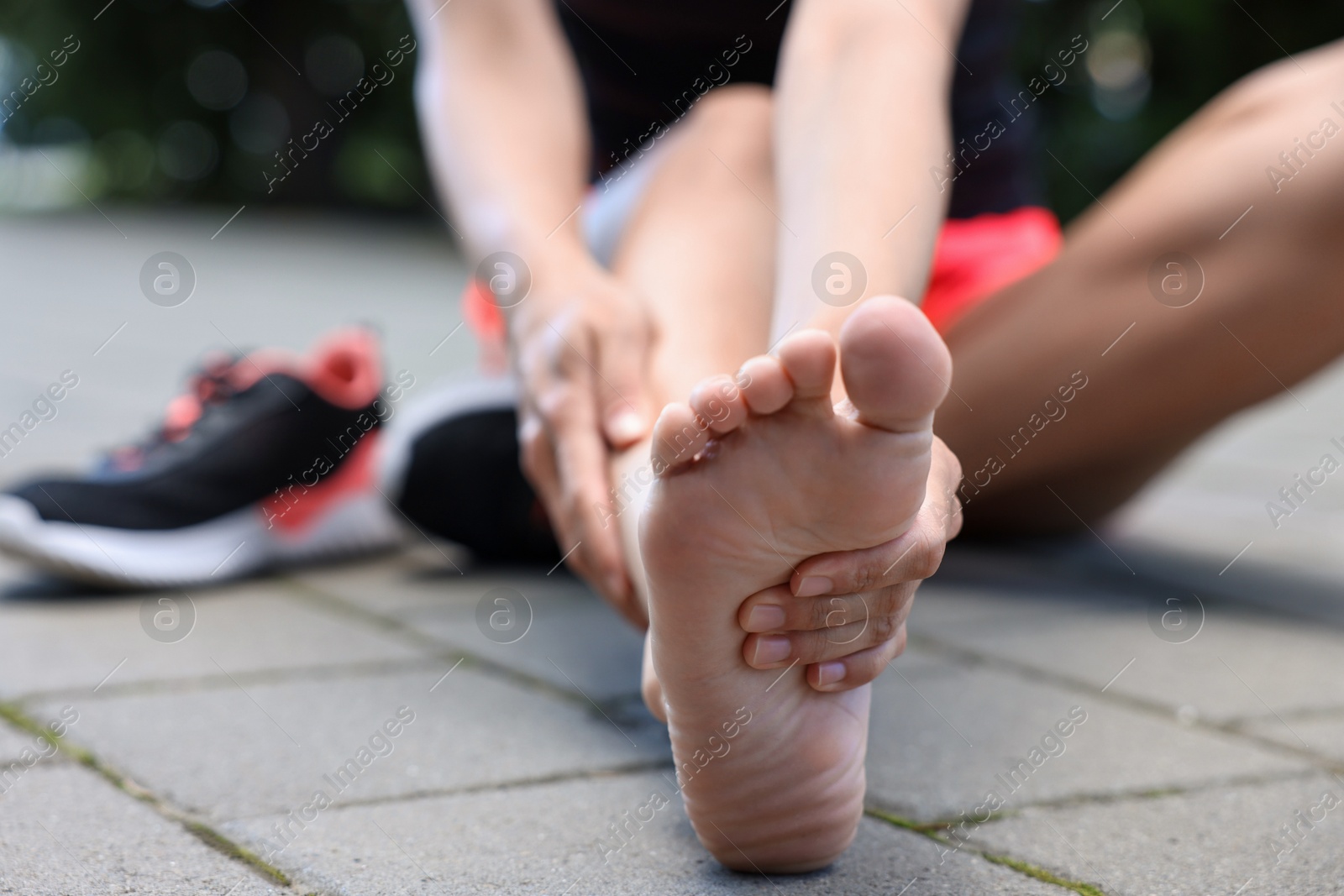 Photo of Woman suffering from foot pain outdoors, closeup