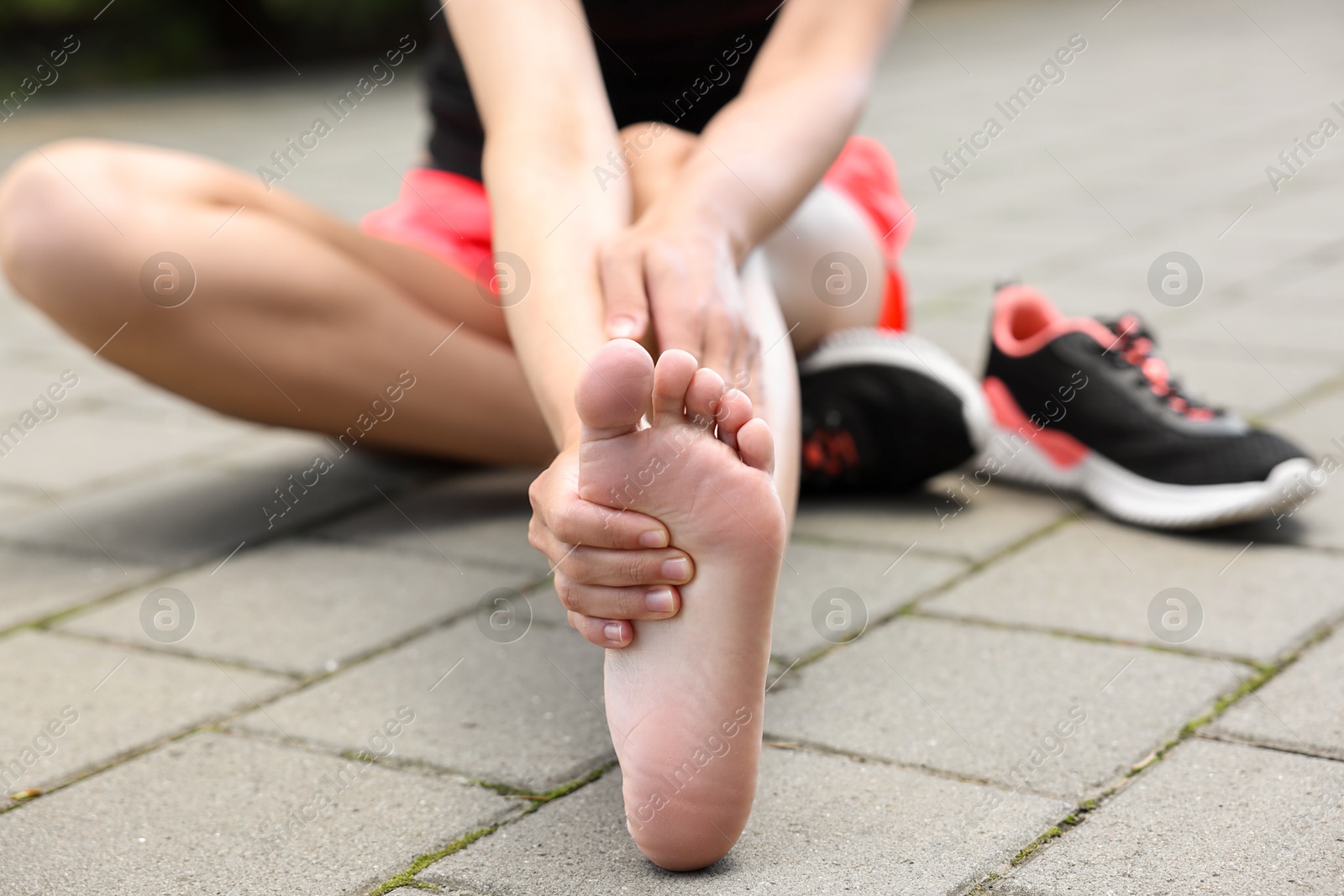 Photo of Woman suffering from foot pain outdoors, closeup