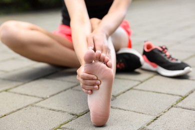 Photo of Woman suffering from foot pain outdoors, closeup