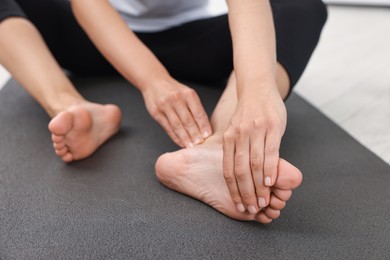 Photo of Woman suffering from foot pain at home, closeup