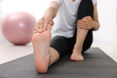 Photo of Woman suffering from foot pain at home, closeup