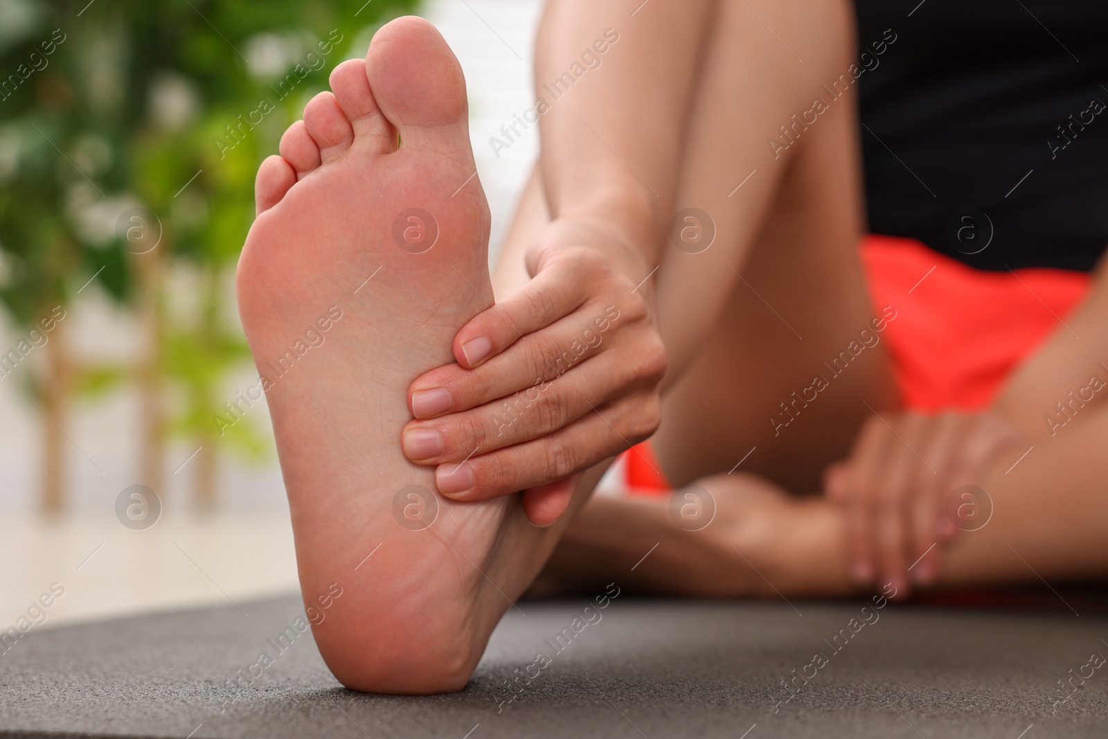 Photo of Woman suffering from foot pain at home, closeup