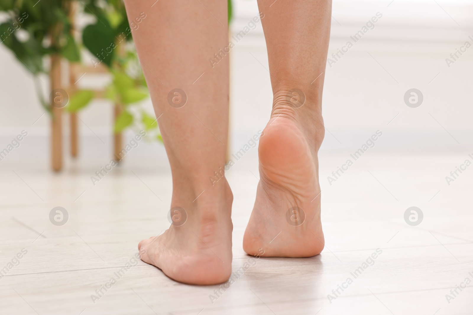 Photo of Woman suffering from foot pain at home, closeup