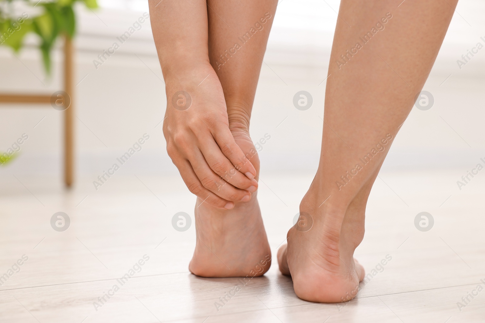 Photo of Woman suffering from foot pain at home, closeup