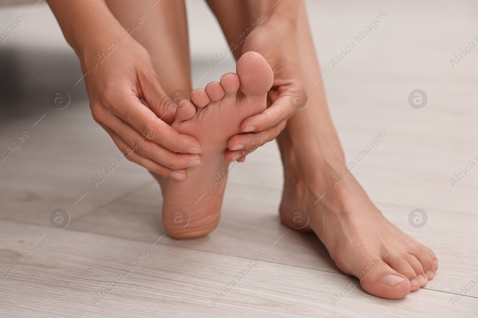 Photo of Woman suffering from foot pain at home, closeup