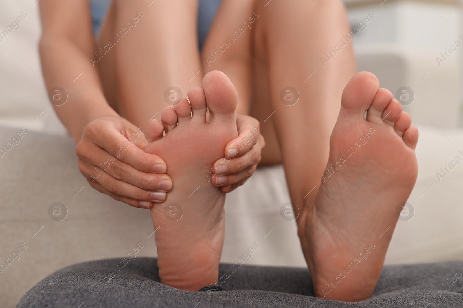 Photo of Woman suffering from foot pain at home, closeup