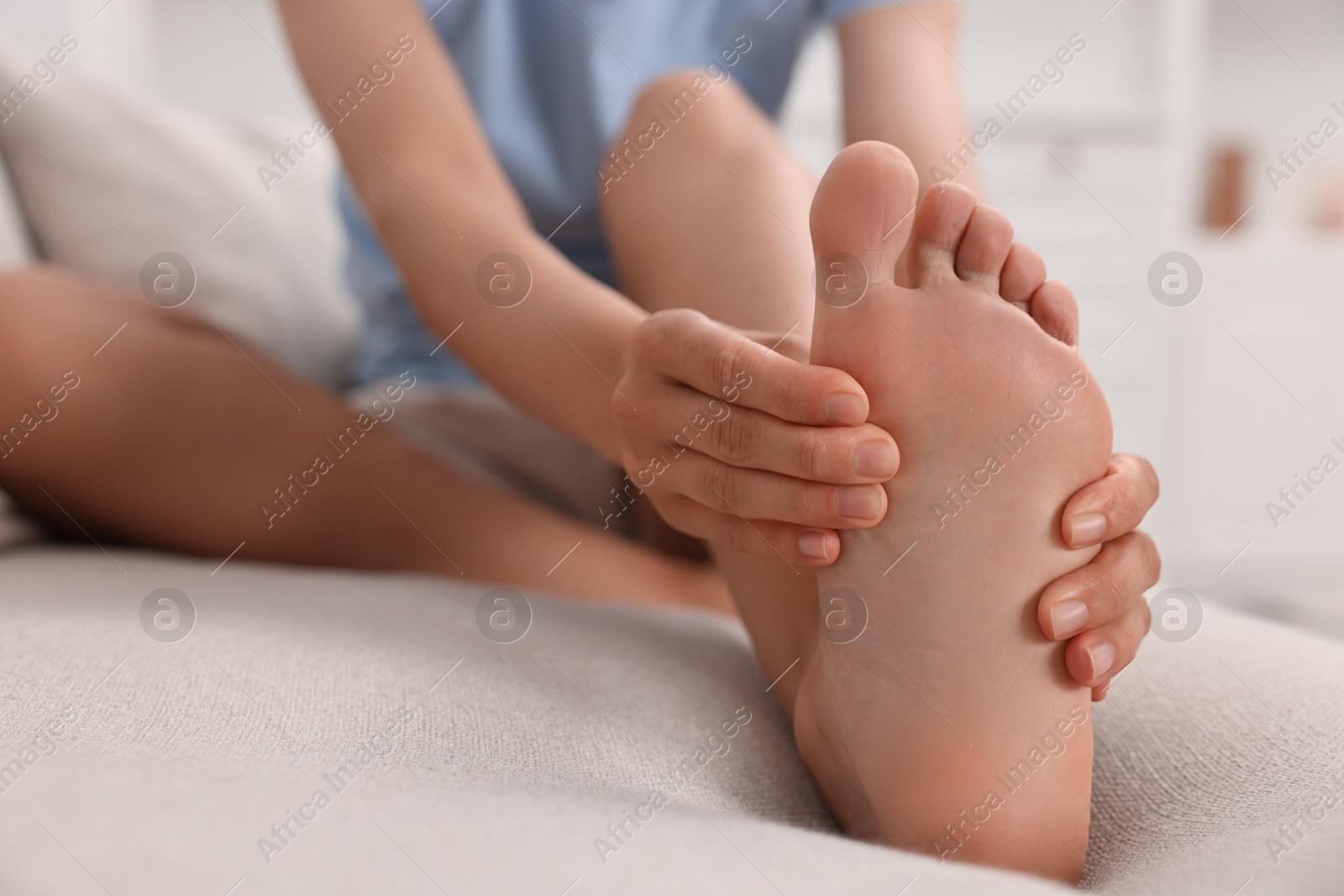 Photo of Woman suffering from foot pain on bed at home, closeup