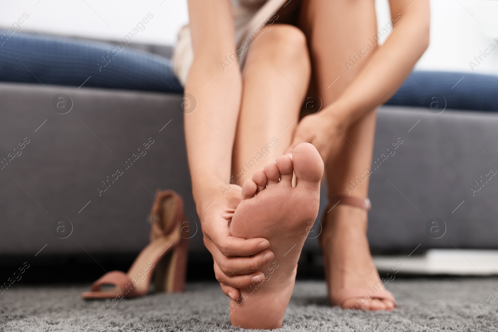 Photo of Woman suffering from foot pain at home, closeup