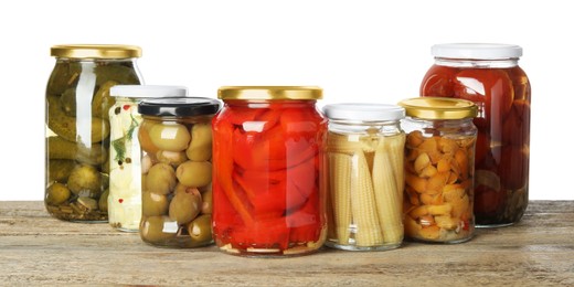 Photo of Different pickled products in jars on wooden table against white background