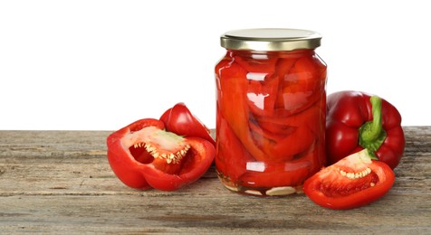 Photo of Tasty pickled bell peppers in jar and fresh vegetables on wooden table against white background