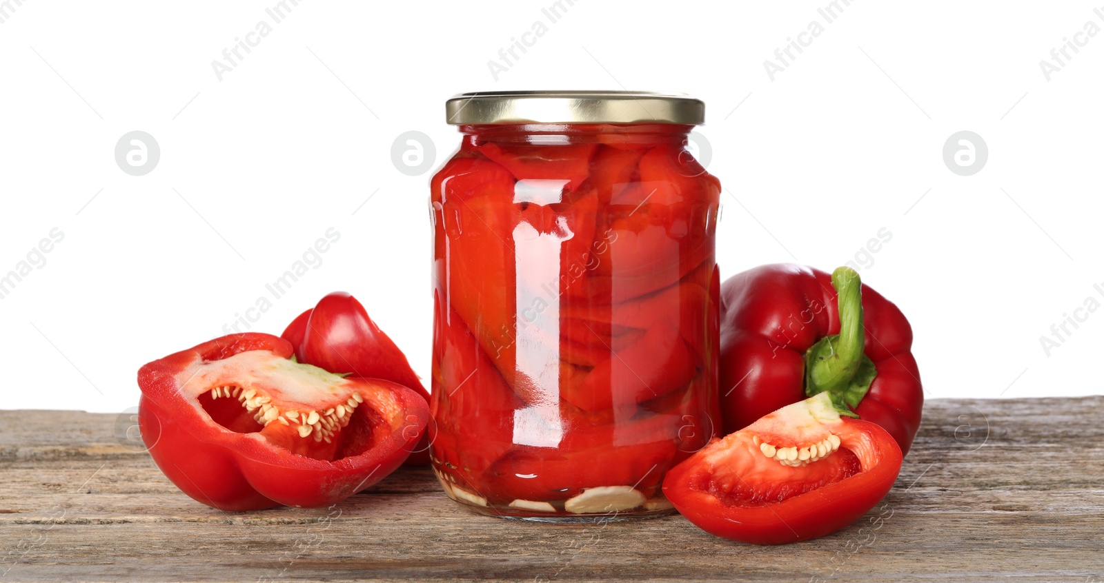 Photo of Tasty pickled bell peppers in jar and fresh vegetables on wooden table against white background