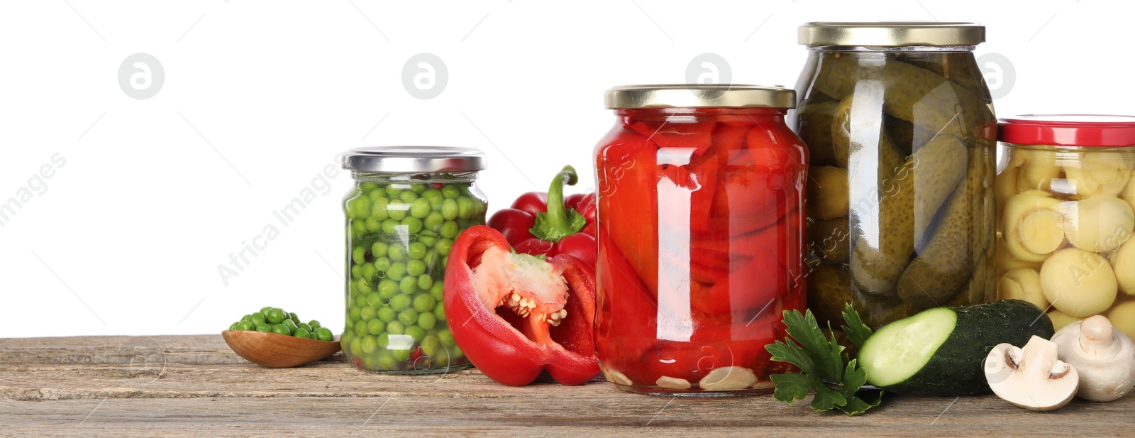 Photo of Different pickled products in jars and fresh ingredients on wooden table against white background