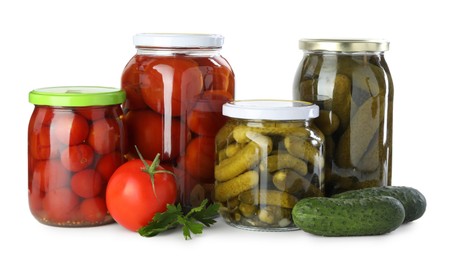 Photo of Tasty pickled vegetables in jars, fresh cucumbers, tomato and parsley isolated on white