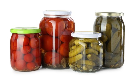 Photo of Tasty pickled tomatoes and cucumbers in jars isolated on white