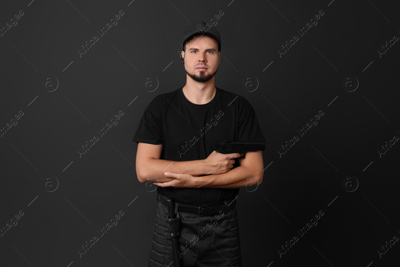 Photo of Young bodyguard with gun on black background