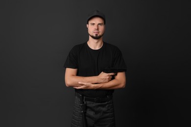 Photo of Young bodyguard with gun on black background