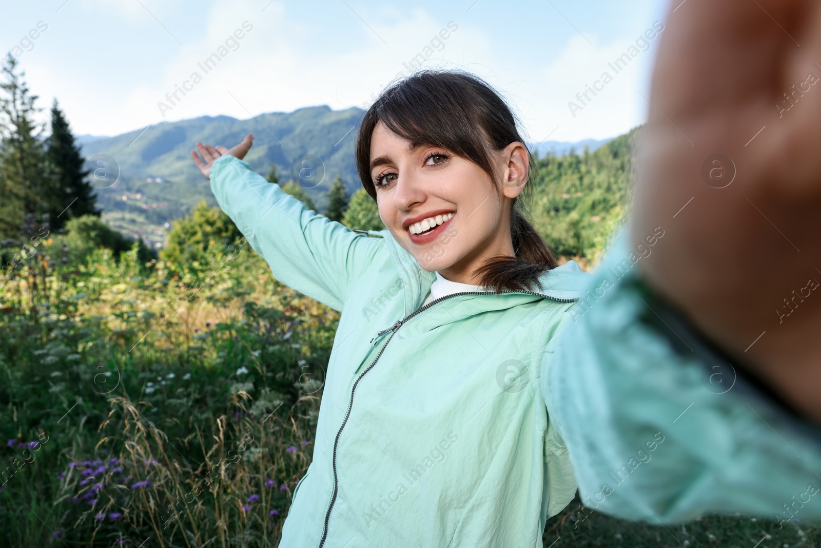 Photo of Smiling woman taking selfie in beautiful mountains