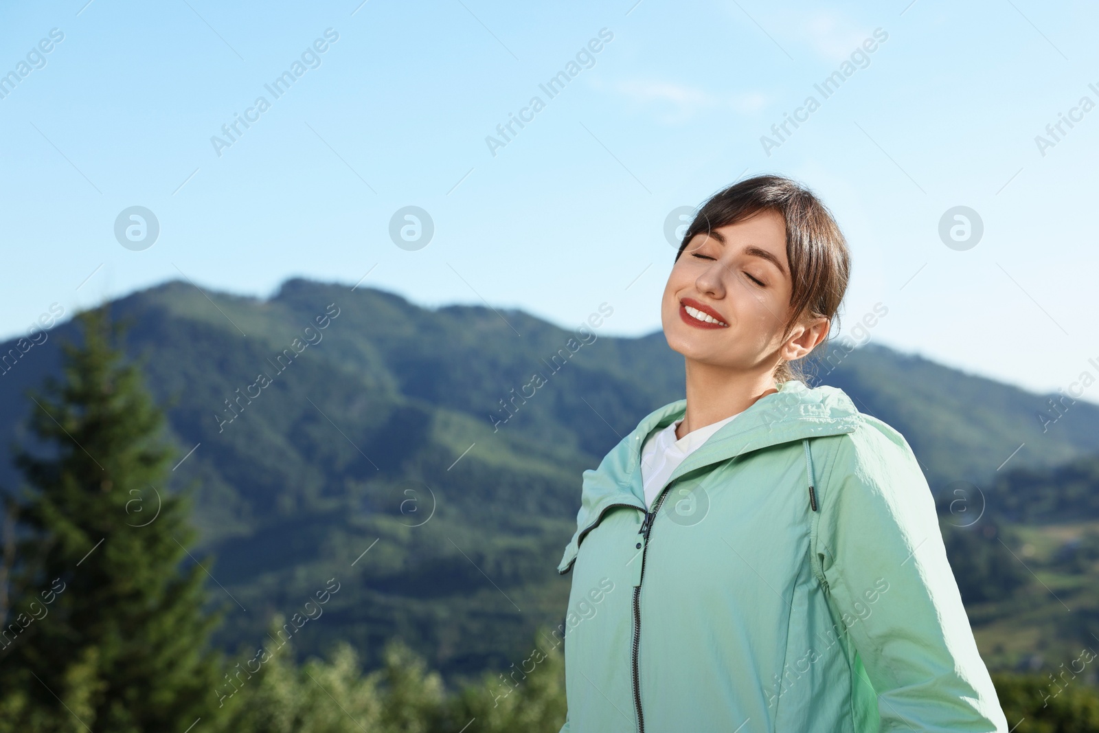 Photo of Smiling woman in beautiful mountains, space for text