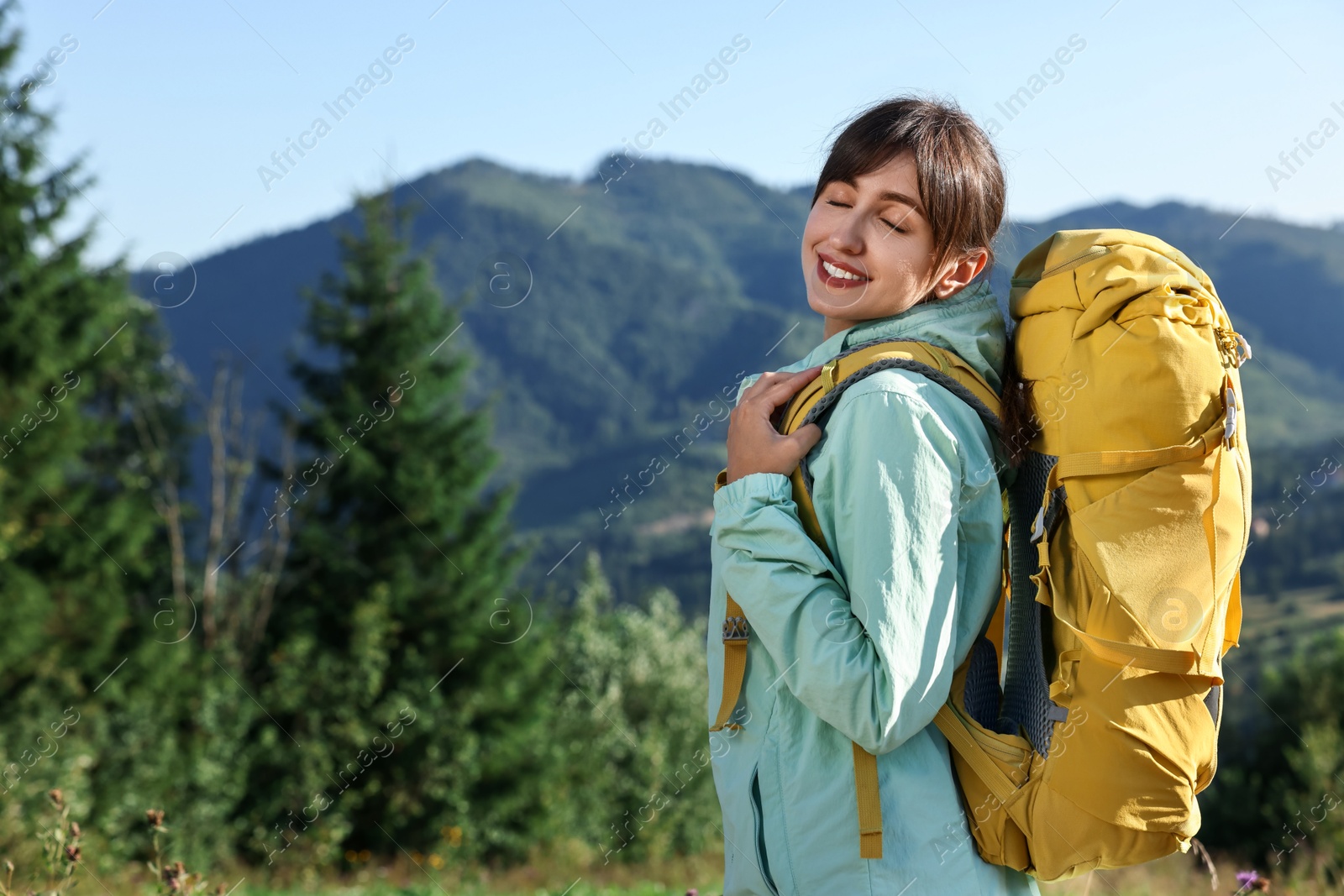 Photo of Smiling woman with backpack in beautiful mountains, space for text